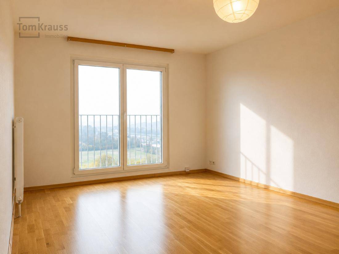 Helles, leeres Schlafzimmer mit Holzboden und französischem Balkon, bereit zur Einrichtung.