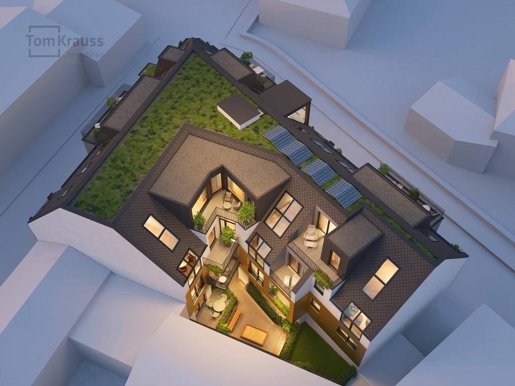 Luftaufnahme eines modernen Wohnkomplexes mit begrüntem Dach, Solaranlagen und Innenhof.