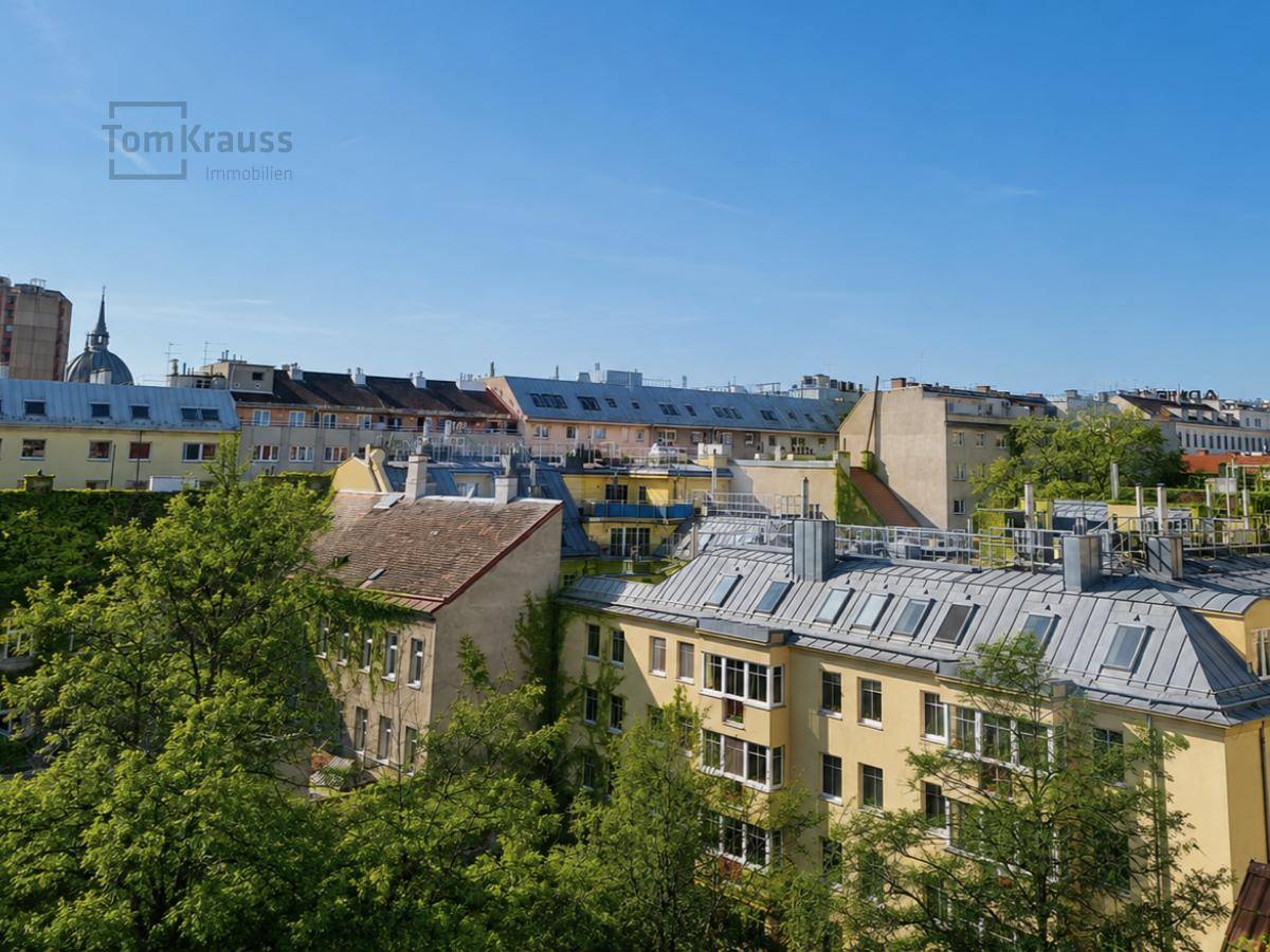 Panoramablick über die Dächer der Stadt mit viel Grün und historischer Architektur.