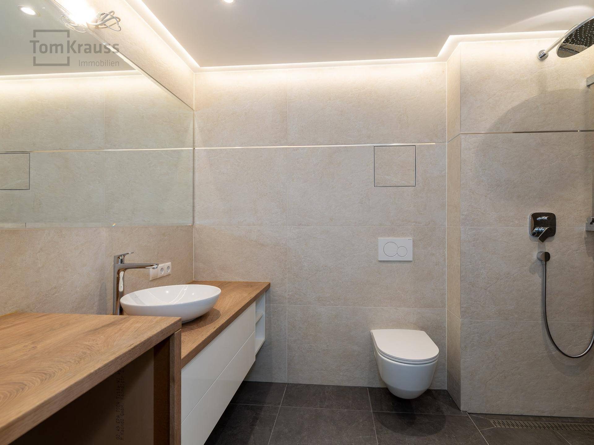 Modernes Badezimmer mit großformatigen Fliesen, Aufsatzwaschbecken und begehbarer Dusche.