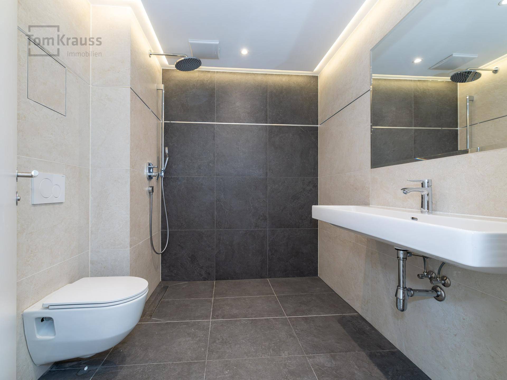 Modernes Badezimmer mit ebenerdiger Dusche, Wand-WC und eleganten Fliesen.