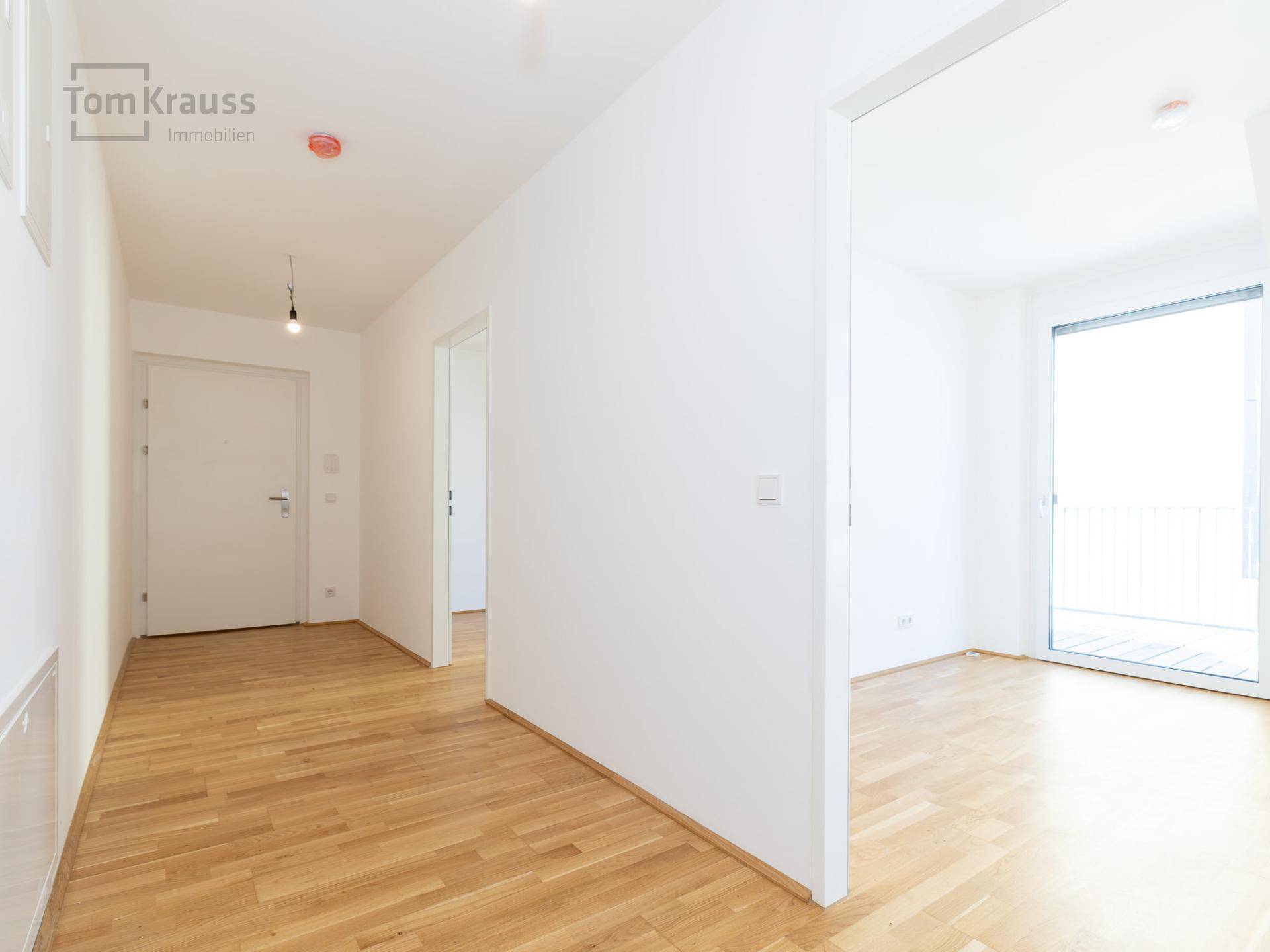 Heller, unmöblierter Flur mit Holzboden und Zugang zu verschiedenen Räumen.