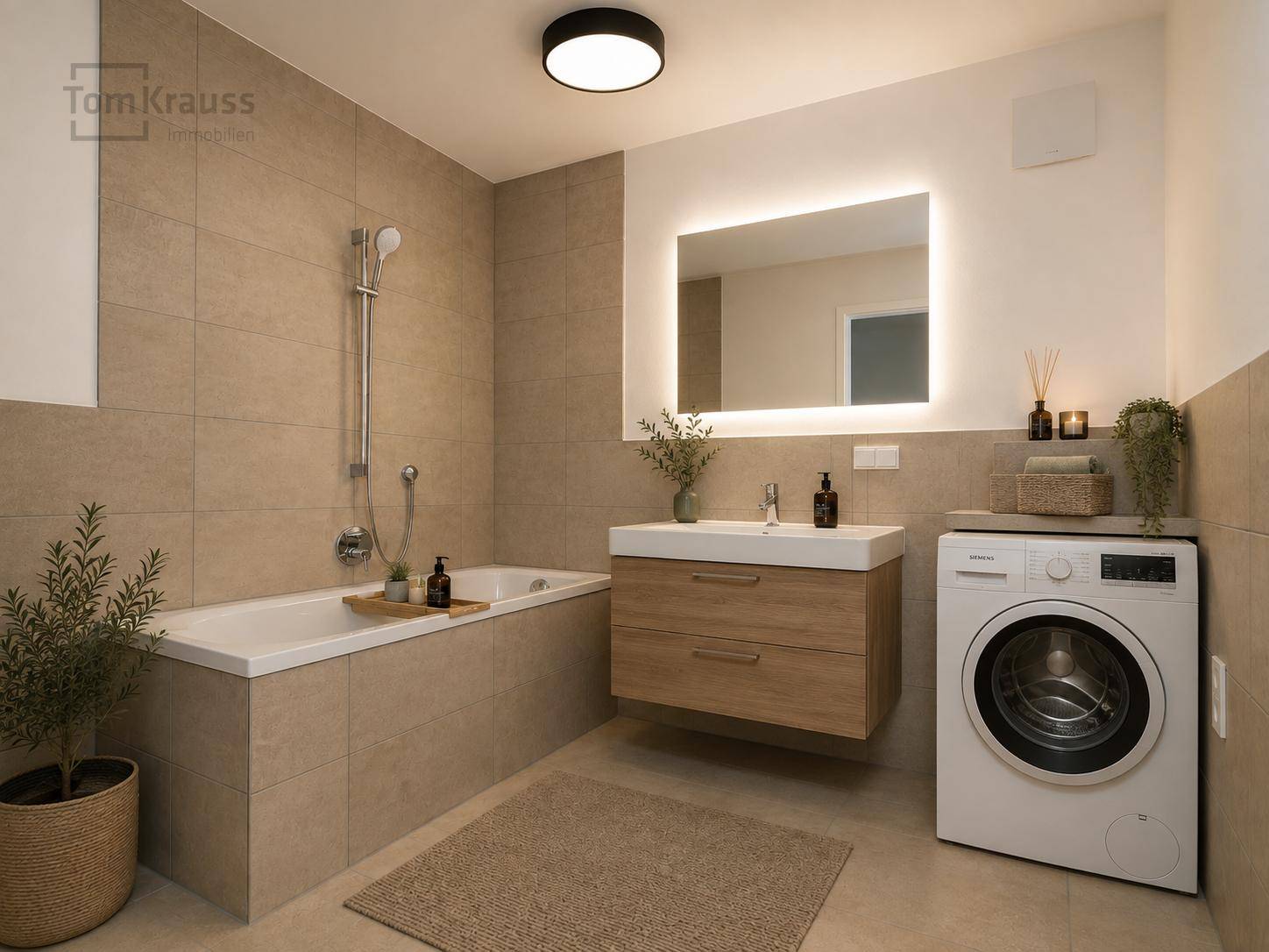 Modernes Badezimmer mit beigefarbenen Fliesen, Badewanne, Waschtisch und integrierter Waschmaschine.