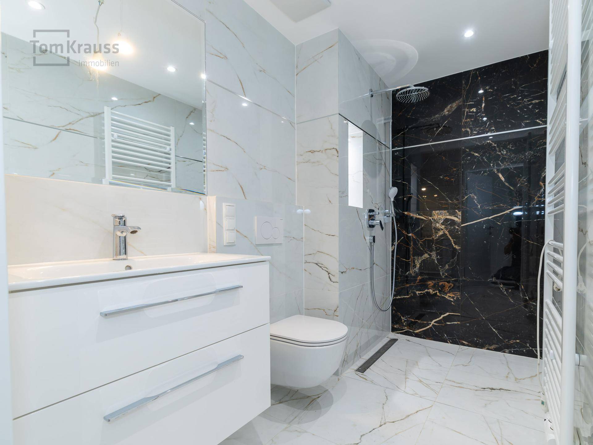 Modernes Badezimmer mit Marmorfliesen, begehbarer Dusche und wandhängendem WC.