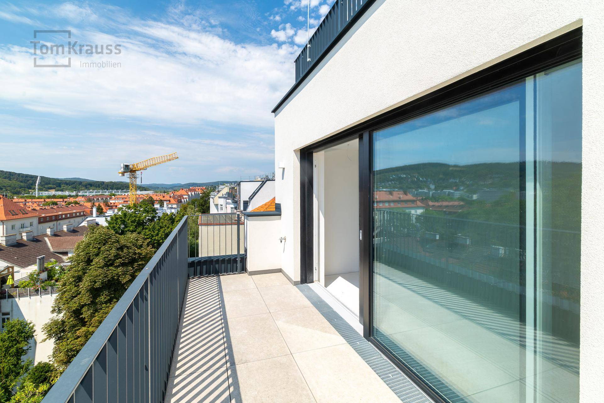 Geräumiger Balkon mit Fliesenboden und weitem Blick über die Stadt und die Landschaft.