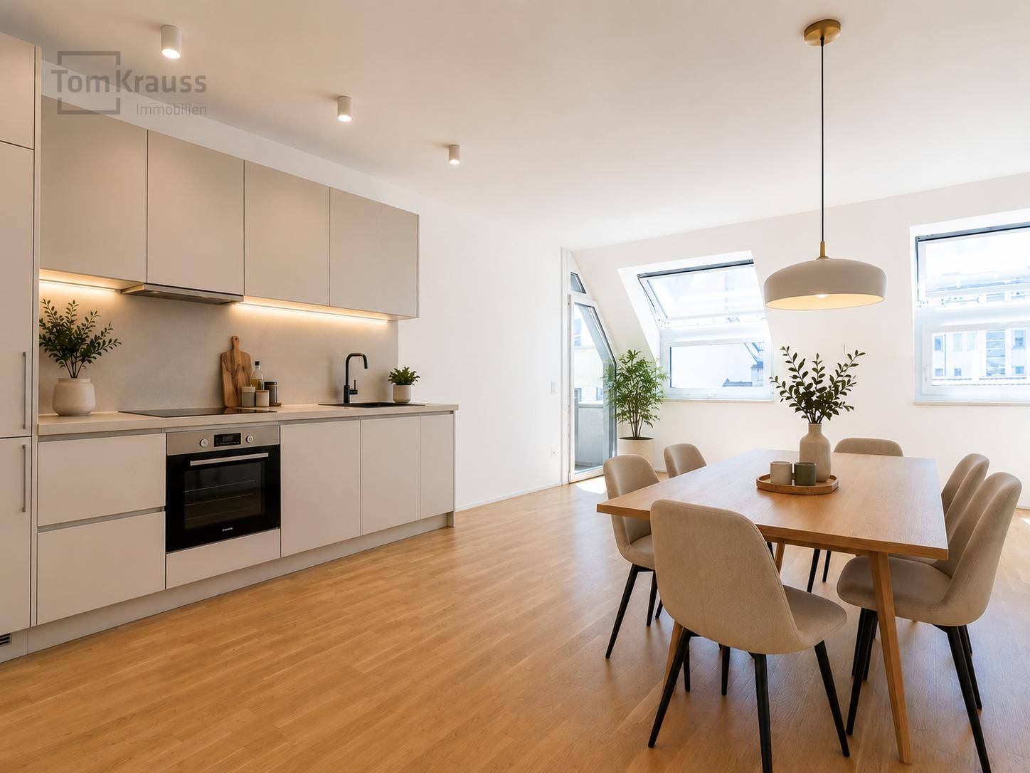 Moderne Wohnküche mit integrierten Geräten, Essbereich und Zugang zu einem Balkon.