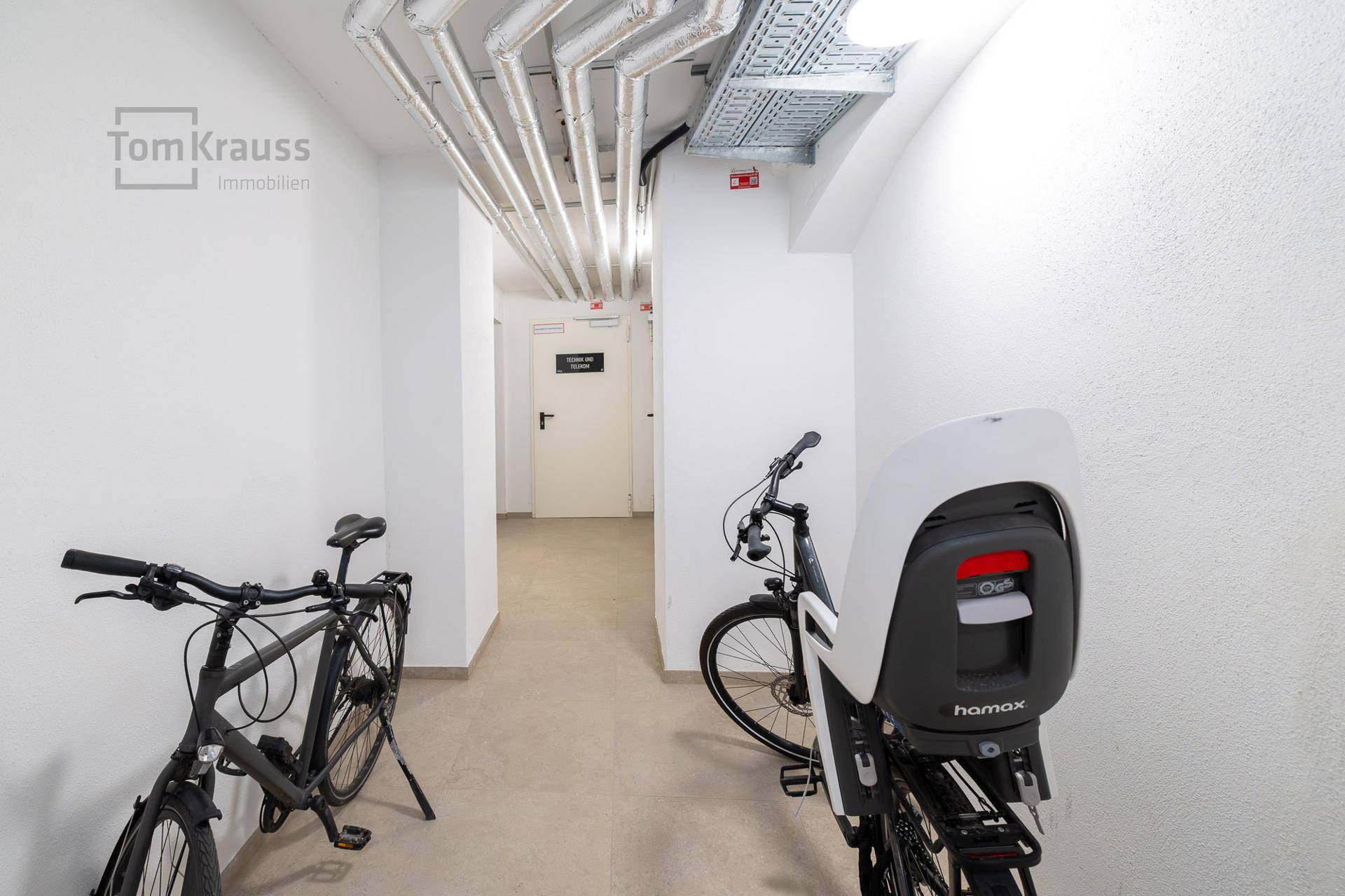 Fahrradraum im Keller mit Fahrrädern und sichtbaren Versorgungsleitungen an der Decke.