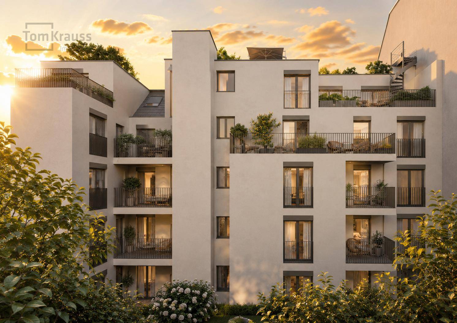 Moderne Wohnanlage mit Balkonen und Terrassen im warmen Licht des Sonnenuntergangs.