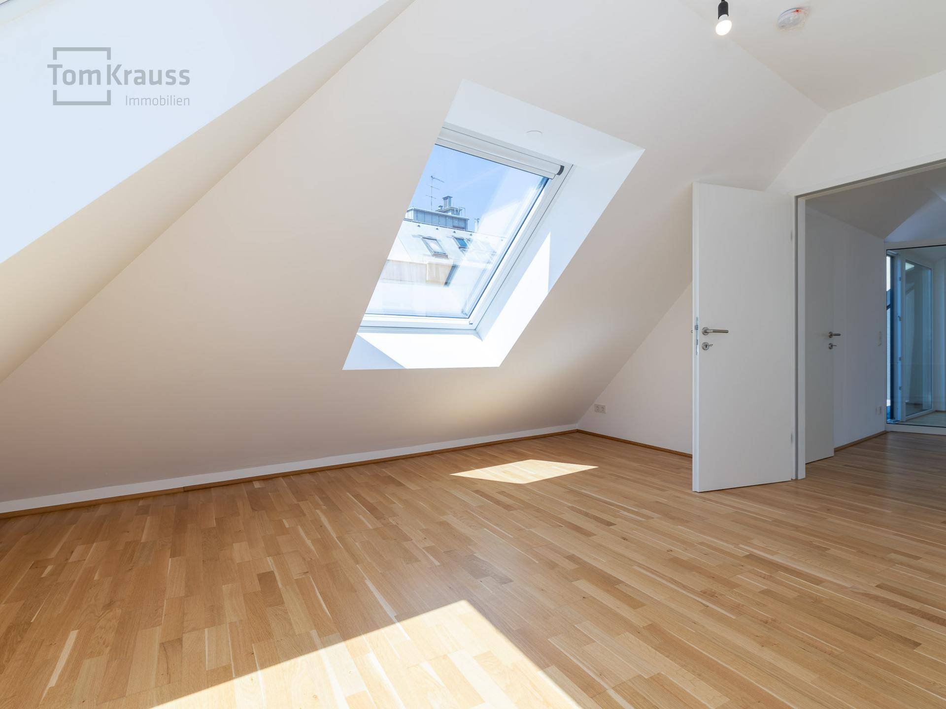 Heller Raum mit Holzboden und großem Dachfenster, bietet viel natürliches Licht und flexible Nutzung.