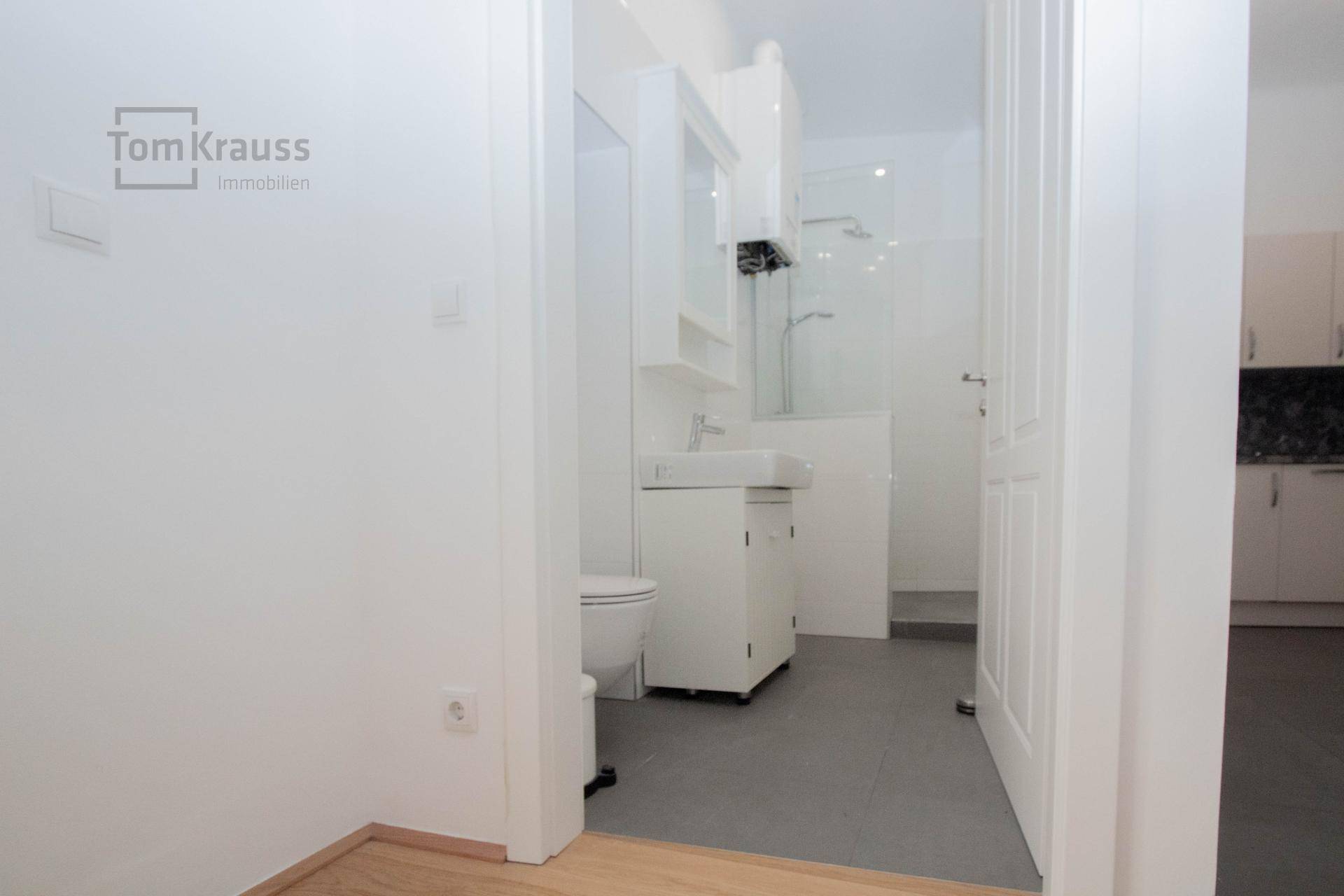 Modernes Badezimmer mit Toilette, Waschbecken, Duschbereich und Gastherme.