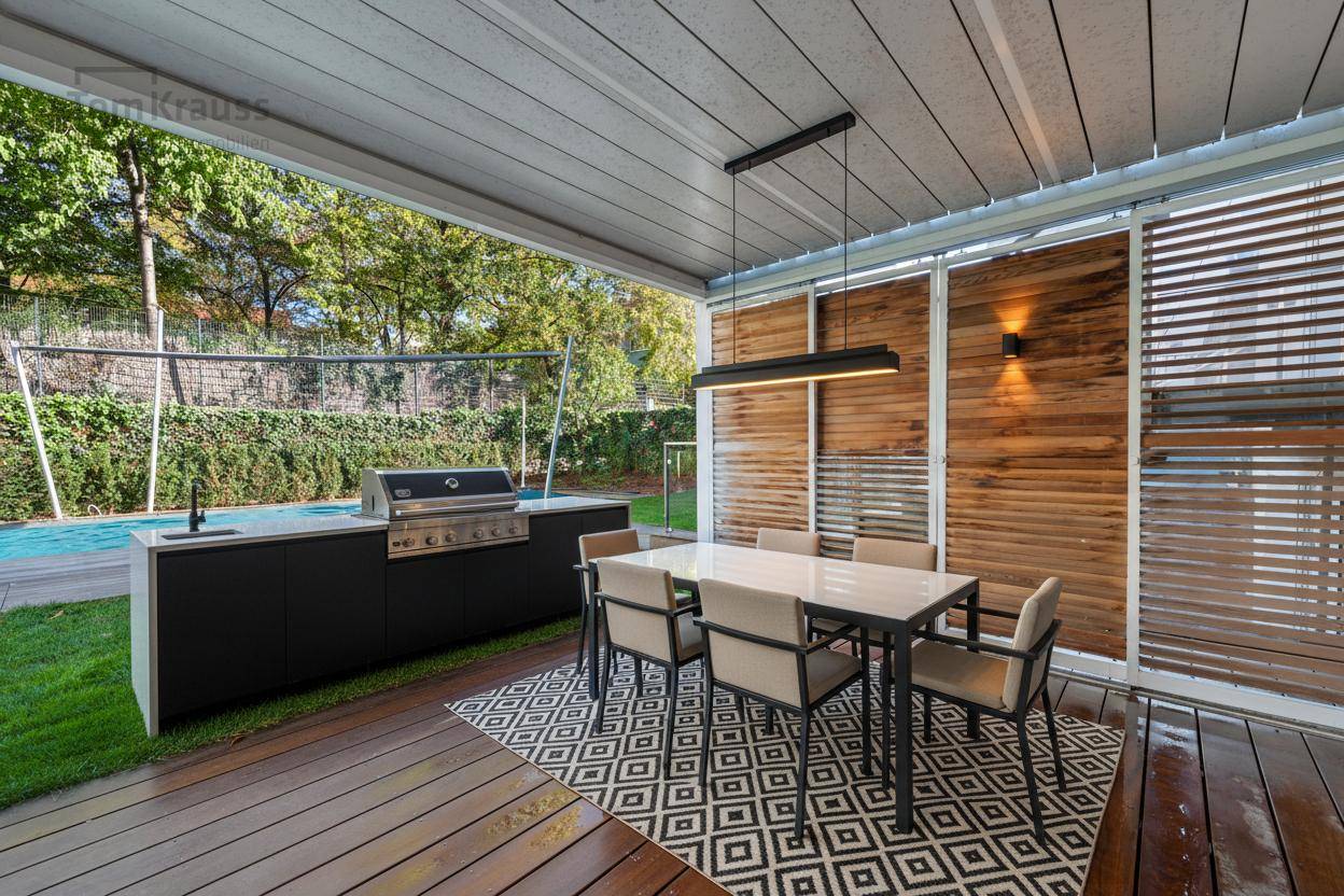 Überdachte Terrasse mit Außenküche, Grillbereich und Esstisch, ideal für gesellige Abende.