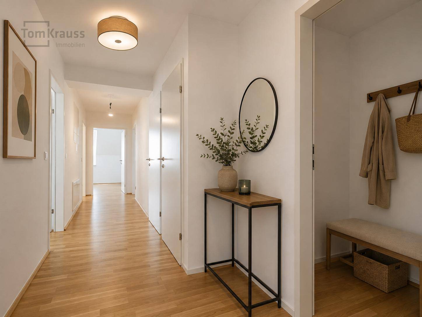 Heller Flur mit Holzboden, Garderobe und einem modernen Konsolentisch mit Spiegel.