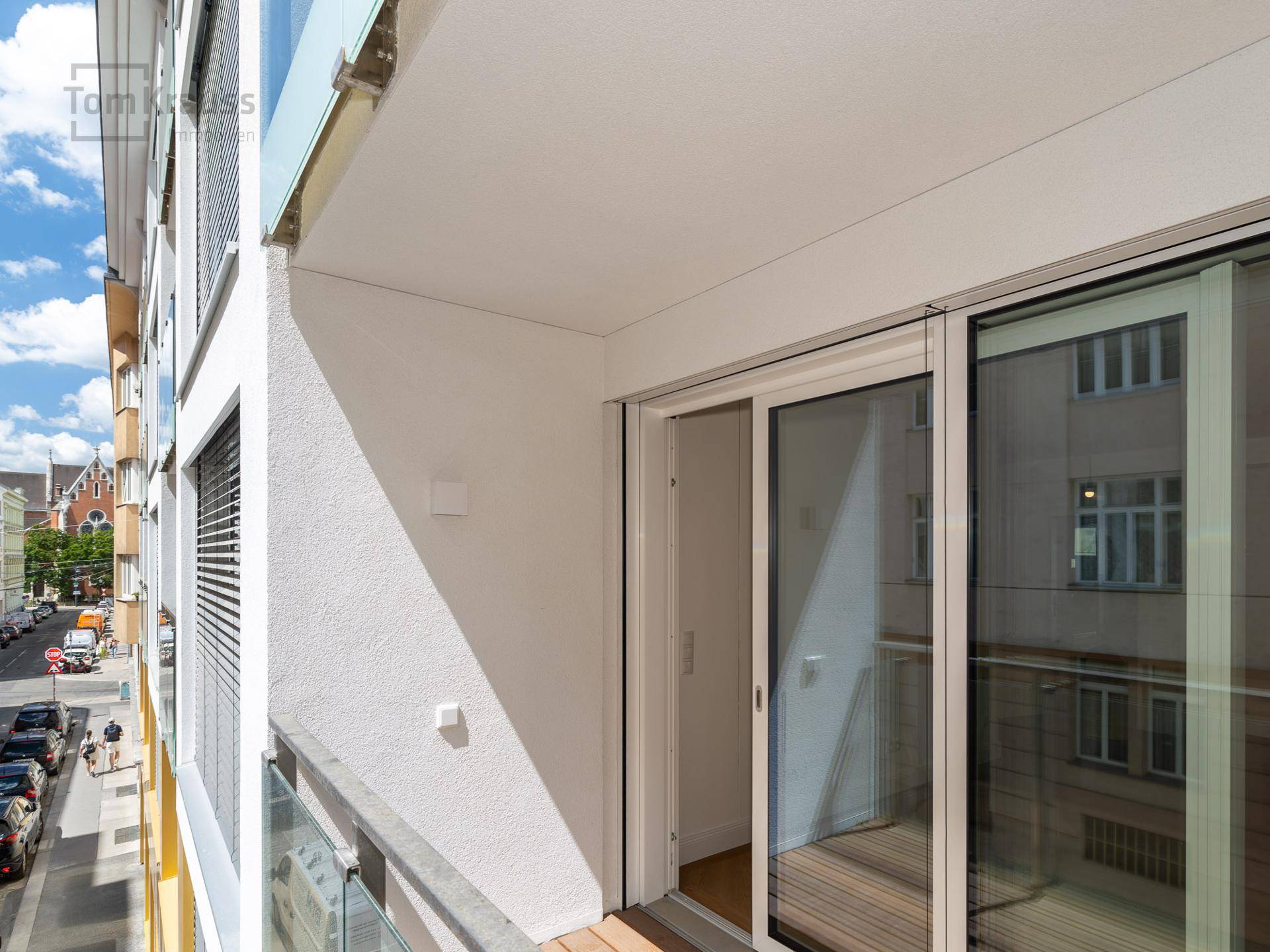 Kleiner Balkon mit Blick auf die Stadtstraße und angrenzende Gebäude.