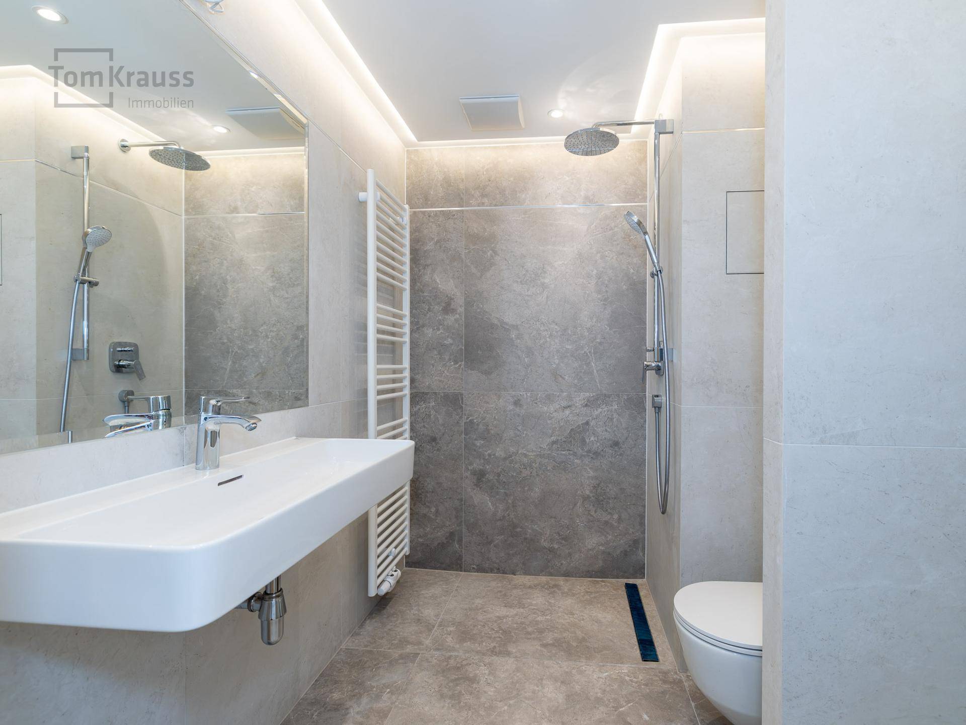 Stilvolles Badezimmer mit Regendusche, Wand-WC und integrierter Beleuchtung.