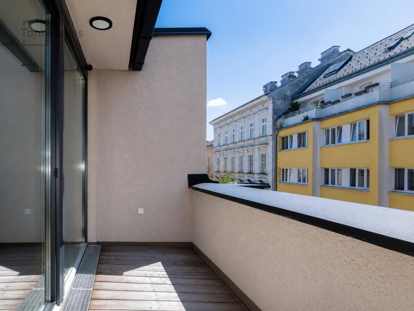 Heller Balkon mit Holzboden und Blick auf die umliegenden Gebäude der Stadt.