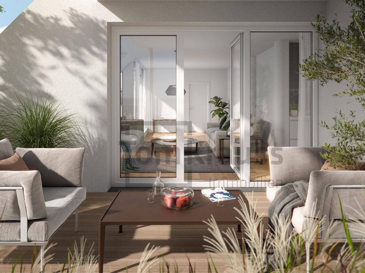 Gemütliche Terrasse mit modernen Sitzmöbeln und Blick durch große Fenster in den hellen Wohnbereich.