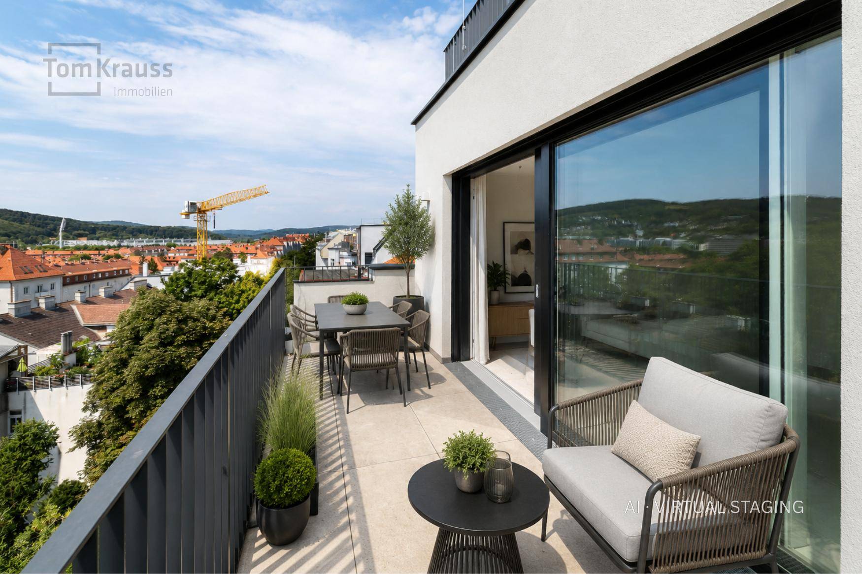 Heller Balkon mit Sitzgelegenheiten und weitem Blick über die Stadt und grüne Hügel.