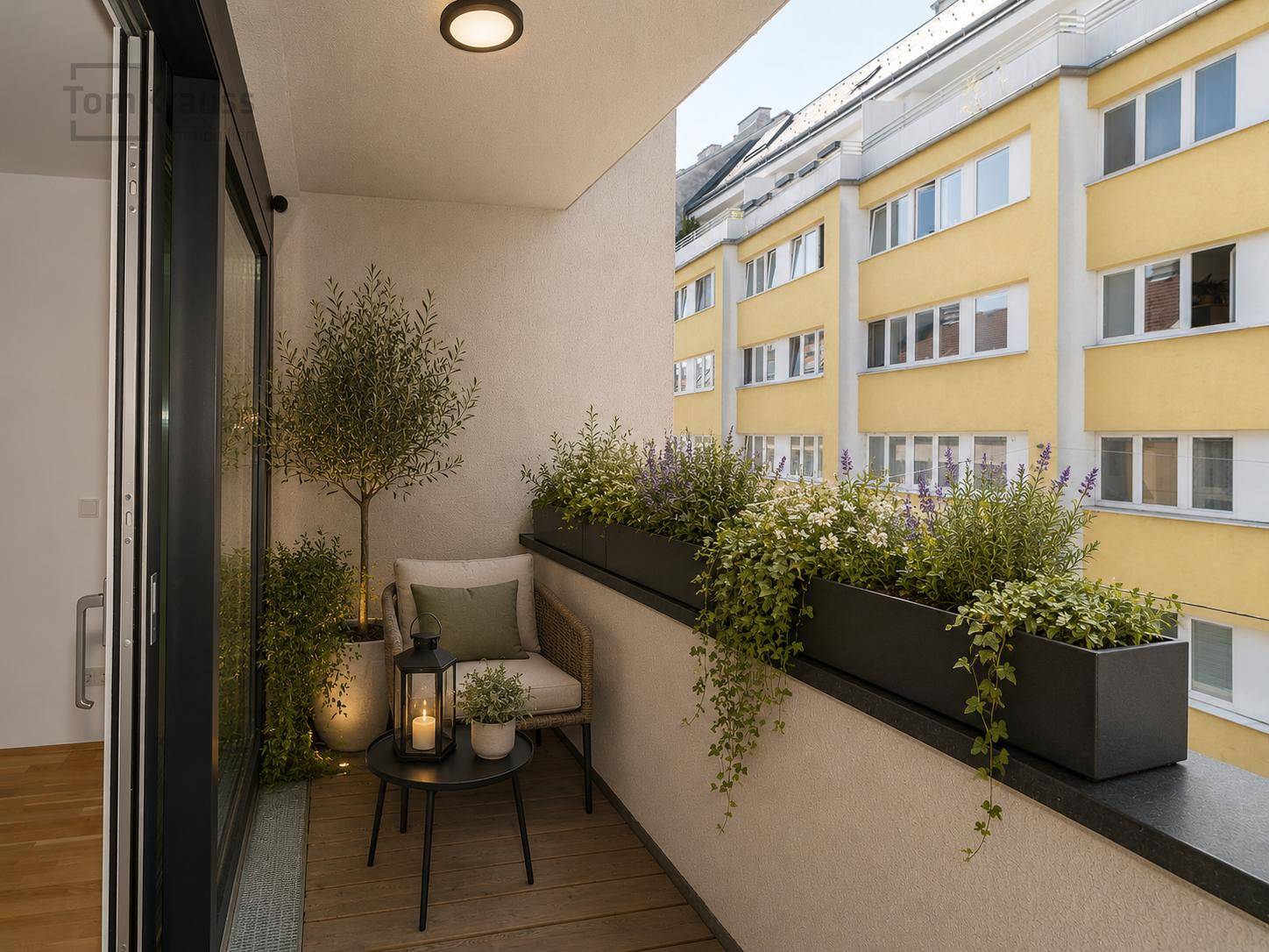 Kleiner, gemütlicher Balkon mit Pflanzen und Sitzgelegenheit, bietet einen Blick auf die Nachbargebäude.