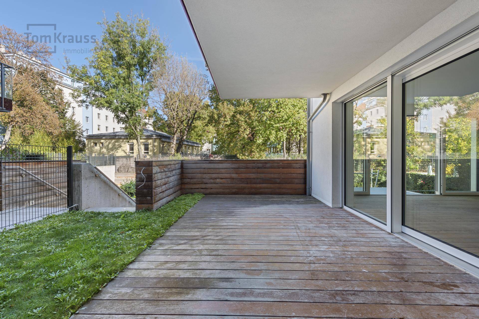 Leere Holzterrasse mit Sichtschutz und großen Schiebetüren zum Innenbereich des Hauses.