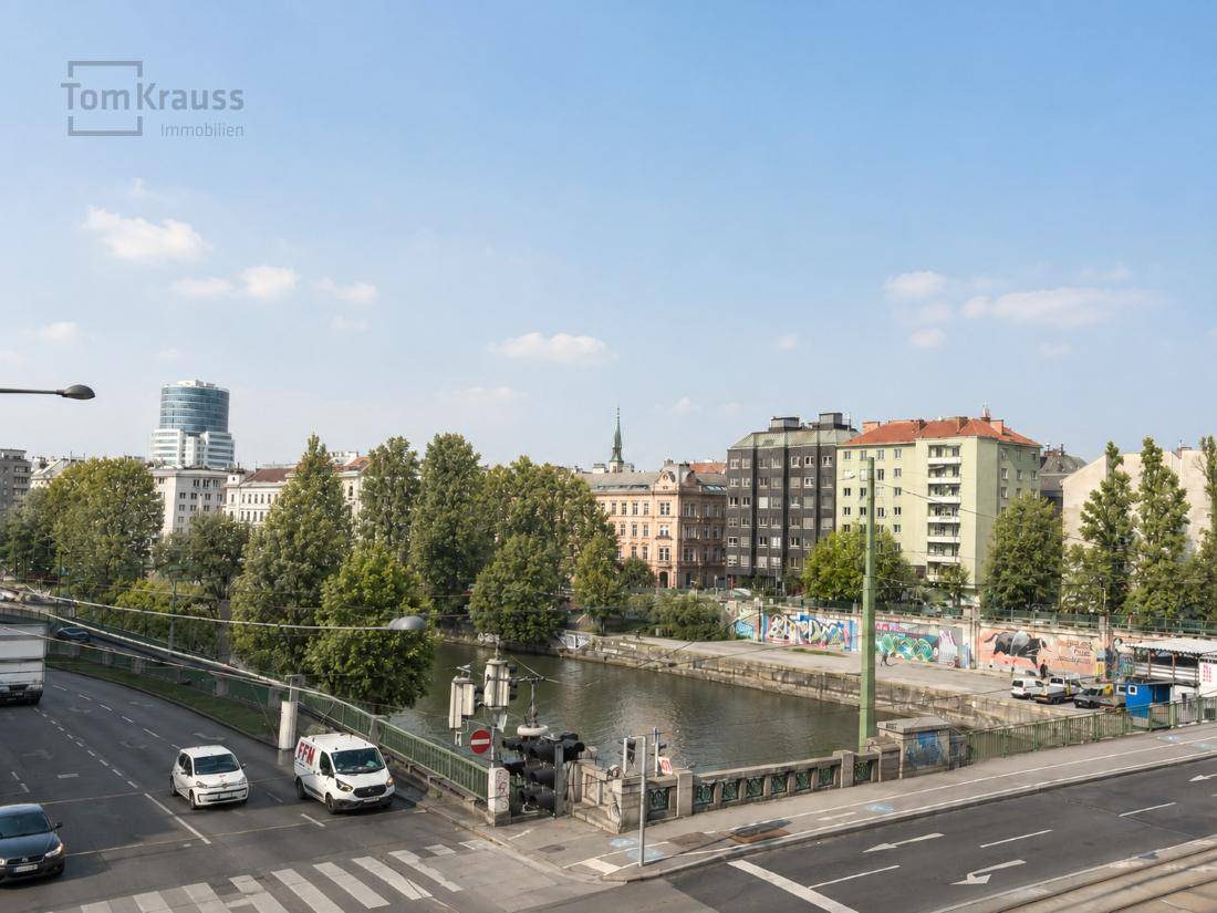 Panoramablick auf den Donaukanal, die umliegende Stadtlandschaft und belebte Straßen.
