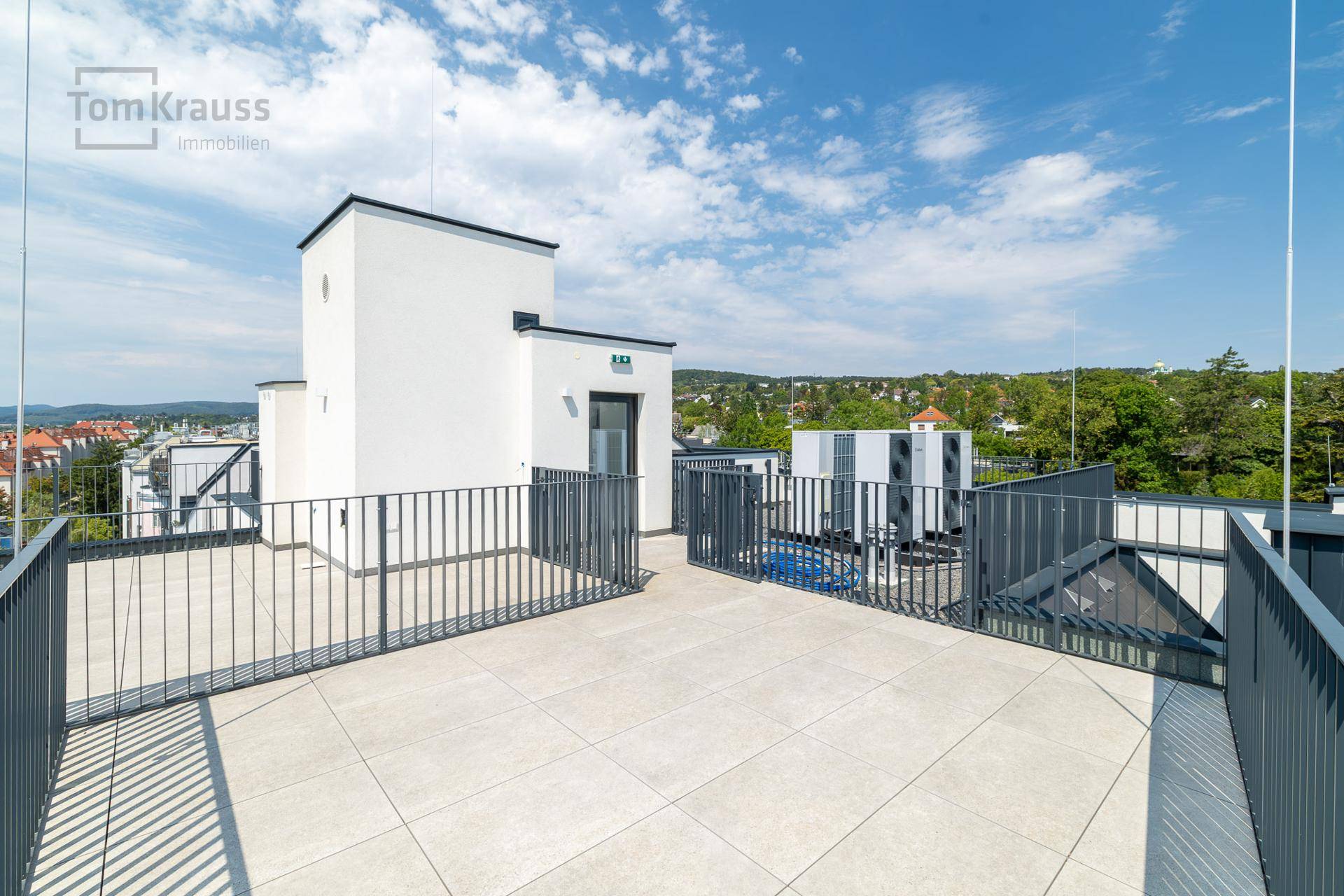 Weitläufige Dachterrasse mit Fliesenboden und Panoramablick über die Stadt und Hügel.