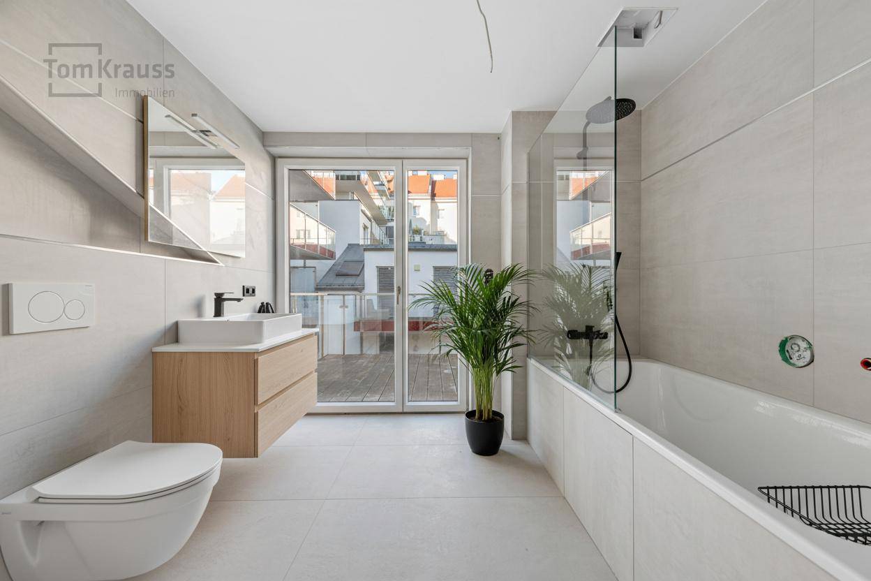 Modernes Badezimmer mit Badewanne, Dusche, Wand-WC und Zugang zu einem Außenbereich.