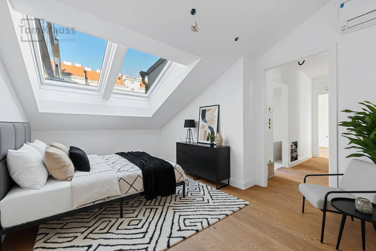 Helles Schlafzimmer mit zwei Dachfenstern, Holzboden und moderner Einrichtung unter der Dachschräge.
