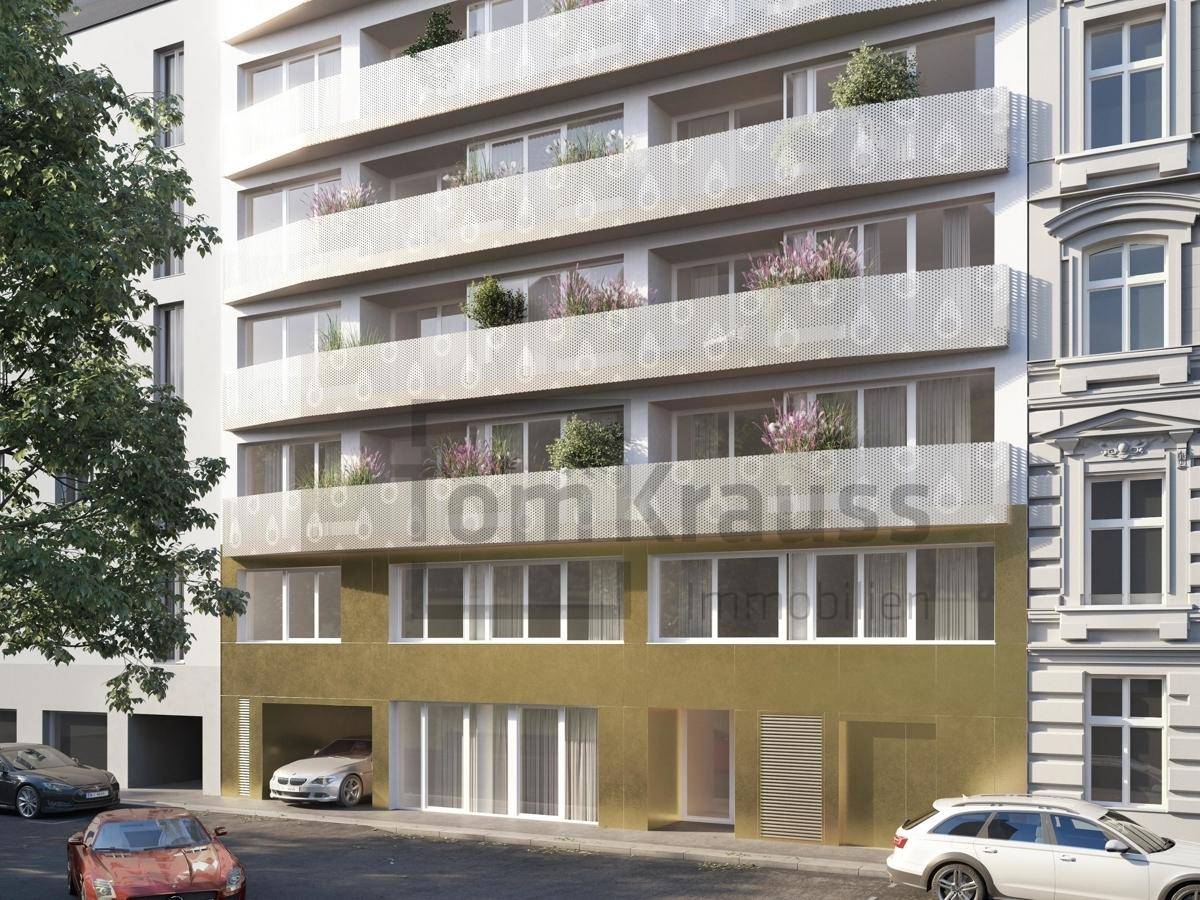 Moderne Gebäudefassade mit Balkonen und goldener Erdgeschossverkleidung.
