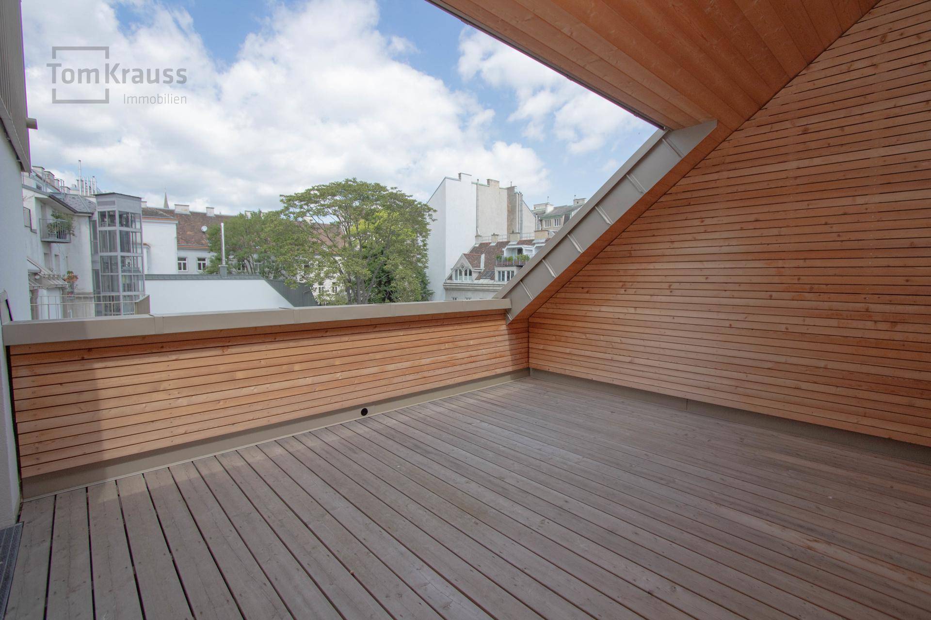 Geräumige Dachterrasse mit Holzboden und Holzverkleidung, bietet einen weiten Stadtblick.