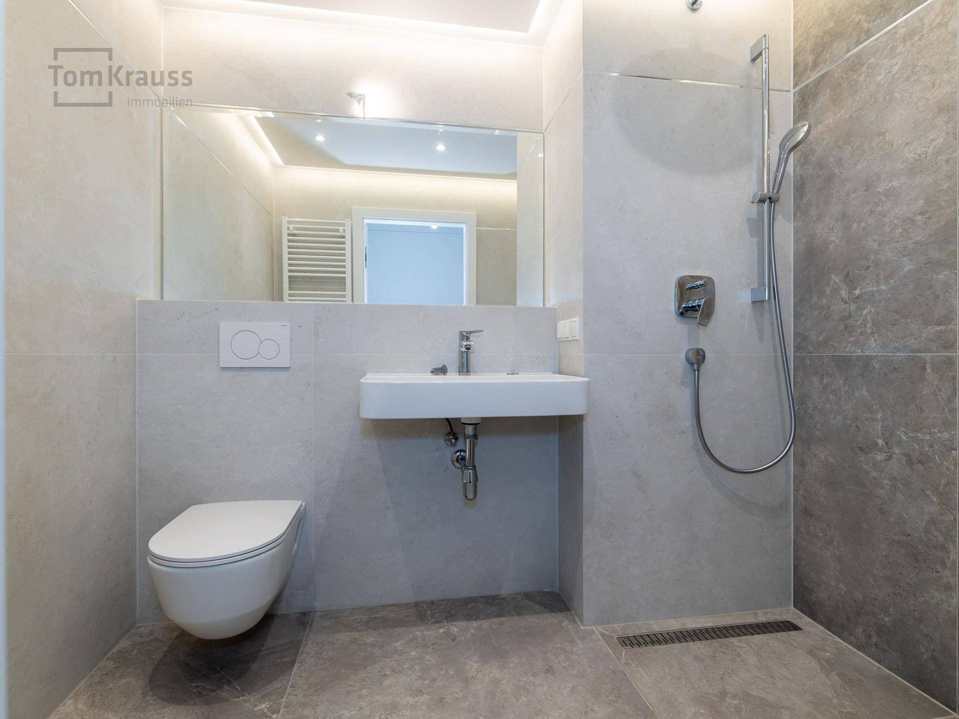 Modernes Badezimmer mit begehbarer Dusche, Wand-WC und eleganten grauen Fliesen.