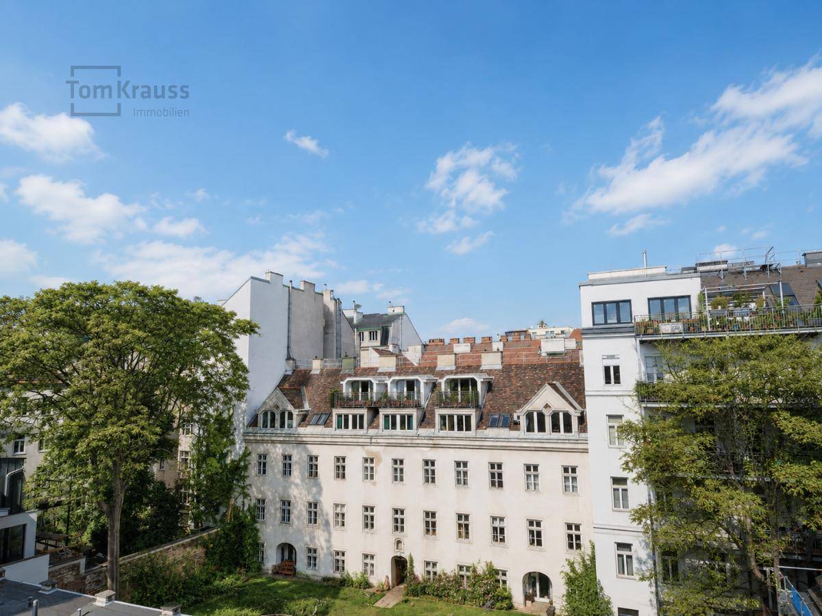 Weitblick über die Dächer der Stadt mit einem historischen Gebäude und viel Grün.