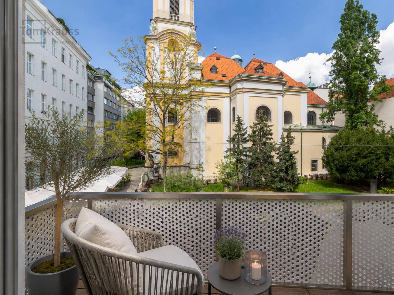Gemütlicher Balkon mit Sitzgelegenheiten und einem malerischen Blick auf eine historische Kirche.