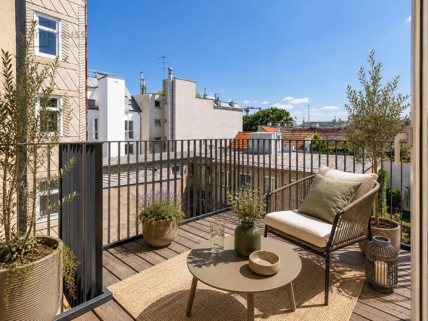 Kleiner Balkon mit Holzboden und Sitzgelegenheiten, bietet einen Blick auf die umliegenden Gebäude.