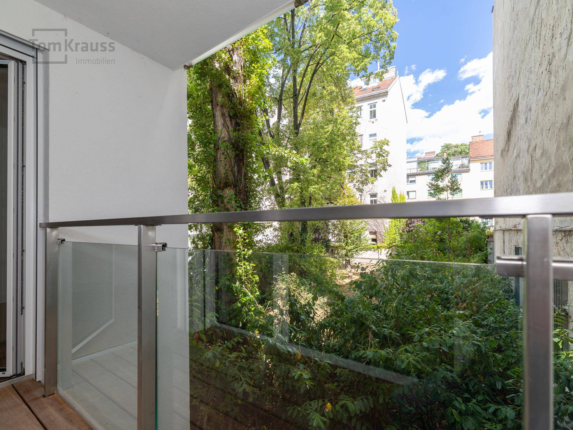Moderner Balkon mit Glasgeländer und Blick ins Grüne, ideal zum Entspannen.