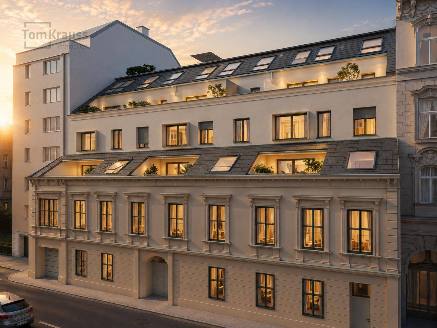 Historisches Gebäude mit modernem Dachausbau und Gaubenfenstern bei Sonnenuntergang.