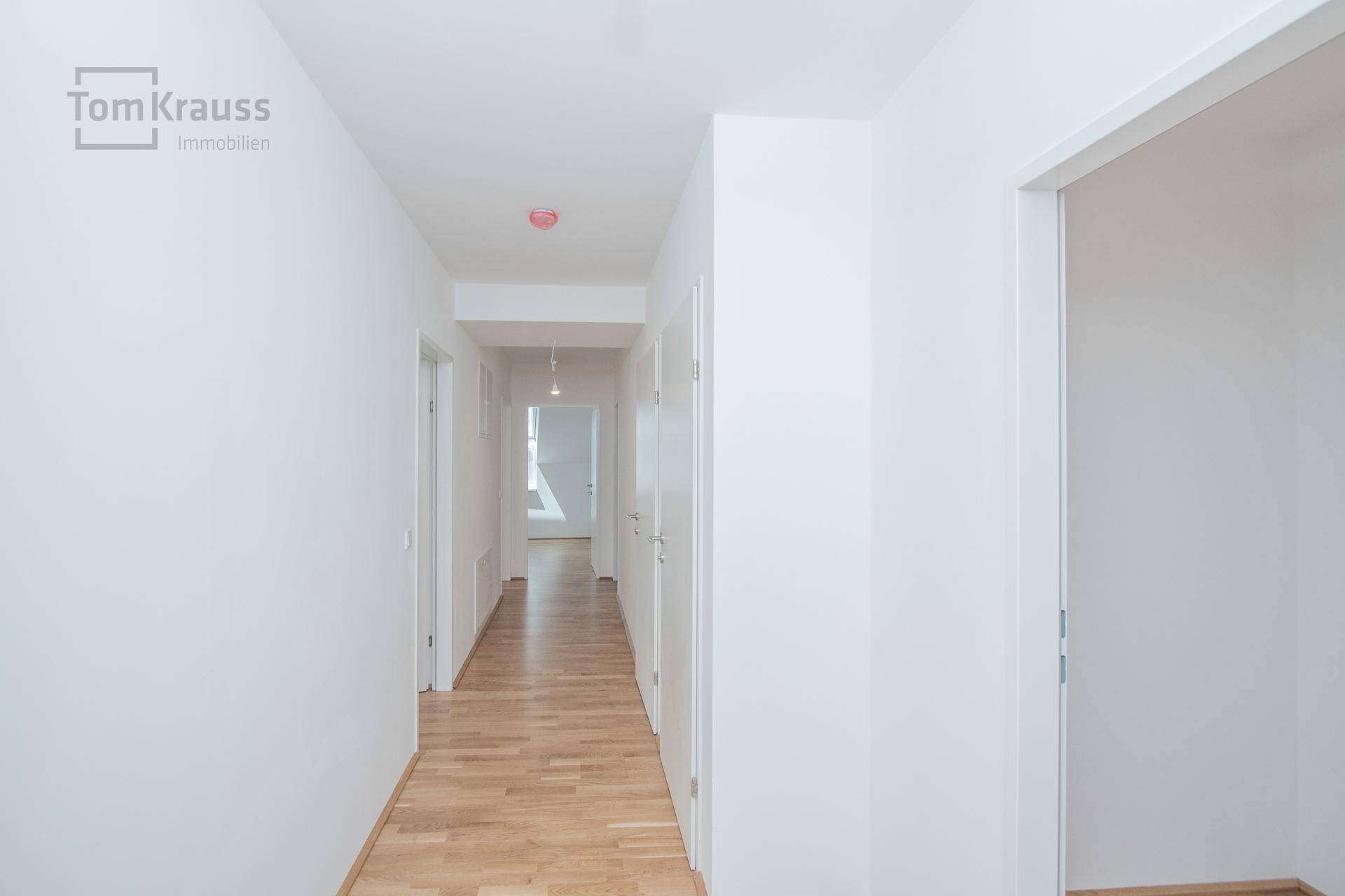 Langer, heller Flur mit Holzparkettboden und Türen zu den angrenzenden Räumen.