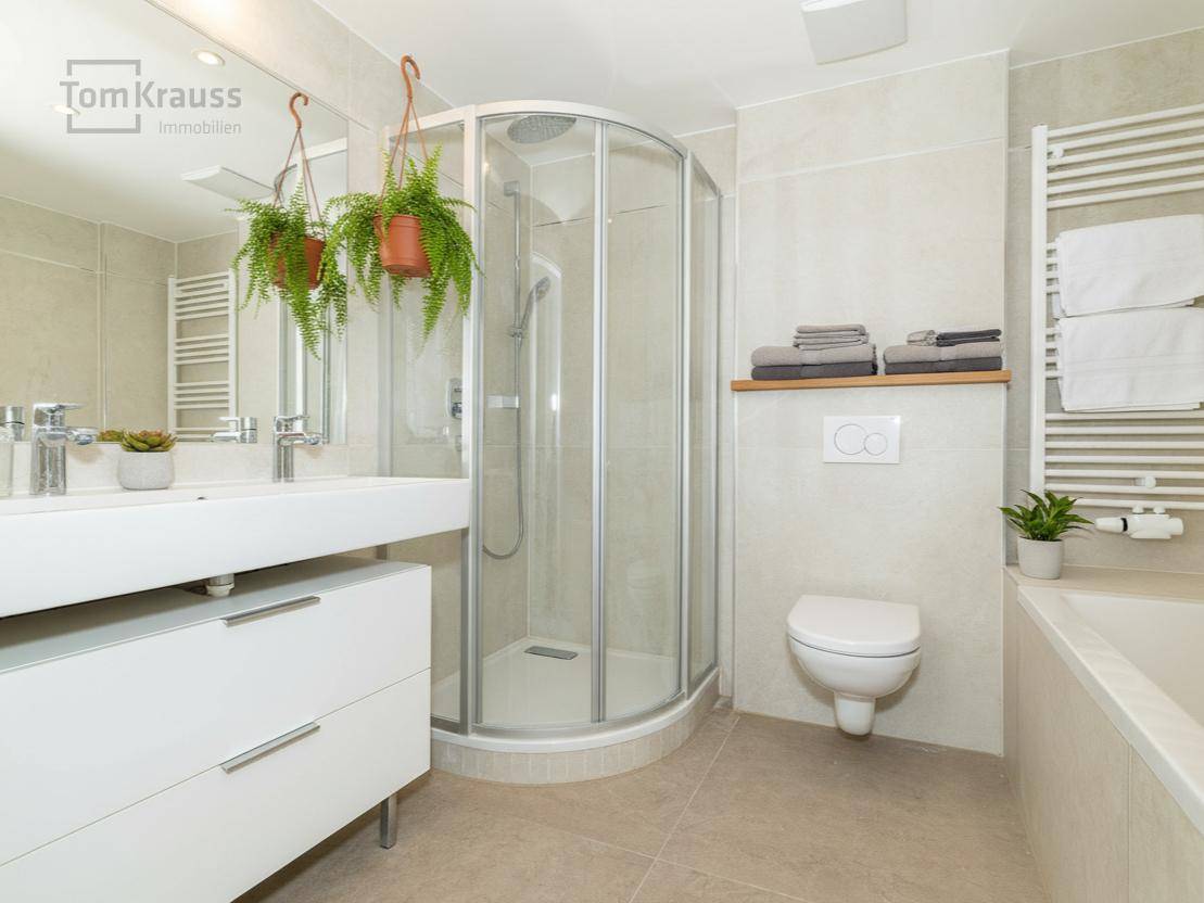 Modernes Badezimmer mit Doppelwaschbecken, Duschkabine und beheiztem Handtuchhalter.