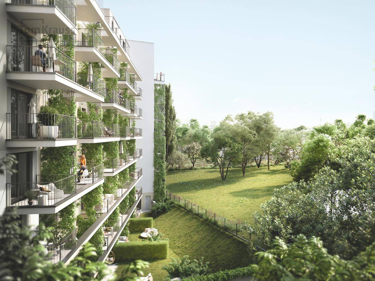 Moderne Wohnfassade mit zahlreichen begrünten Balkonen und Blick auf eine weitläufige Grünfläche.