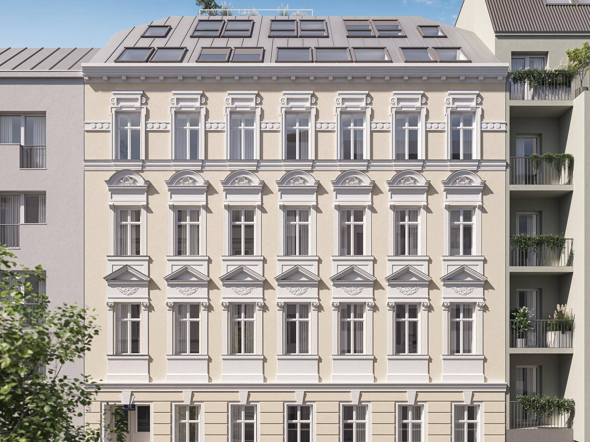 Historische Fassade eines Altbaus mit verzierten Fenstern und modernem Dachausbau mit Dachfenstern.