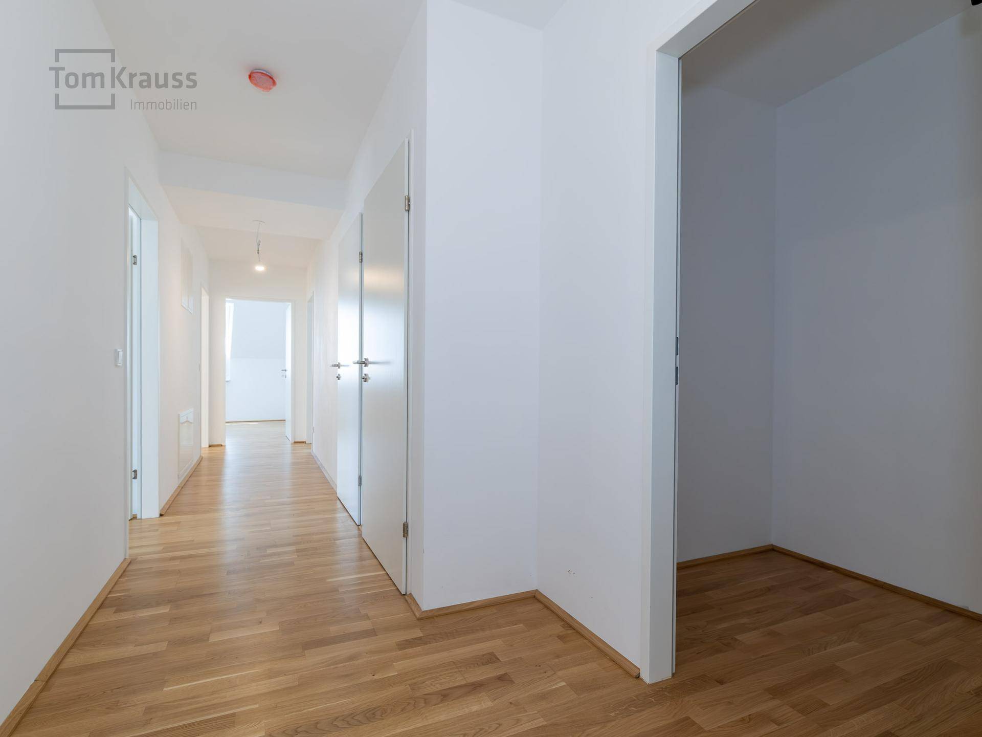 Langer, heller Flur mit Holzparkettboden und mehreren Türen zu den angrenzenden Räumen.