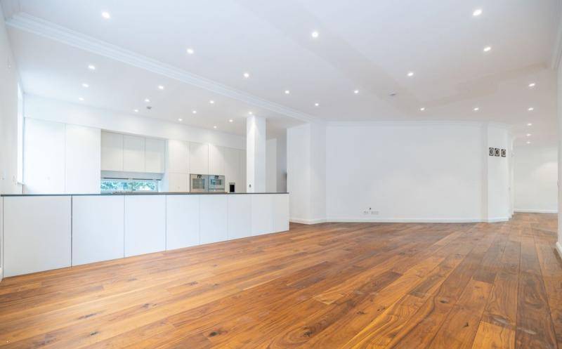 Weitläufiger Wohnbereich mit integrierter, minimalistischer Küche und elegantem Holzboden.