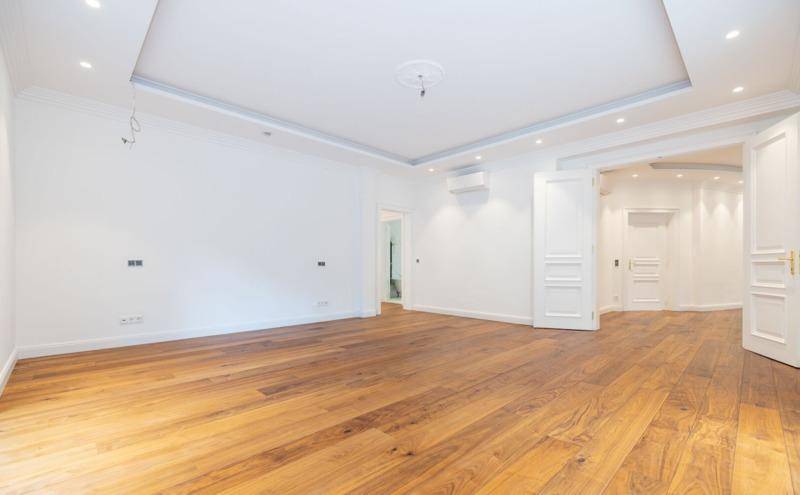 Geräumiges Zimmer mit Holzboden, abgehängter Decke und Zugang zu weiteren Räumen.
