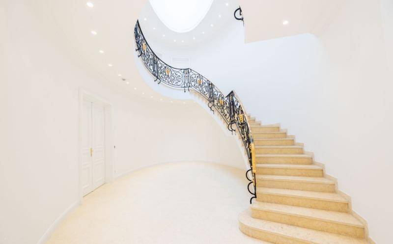 Elegante geschwungene Treppe mit kunstvollem Geländer und Marmorstufen.