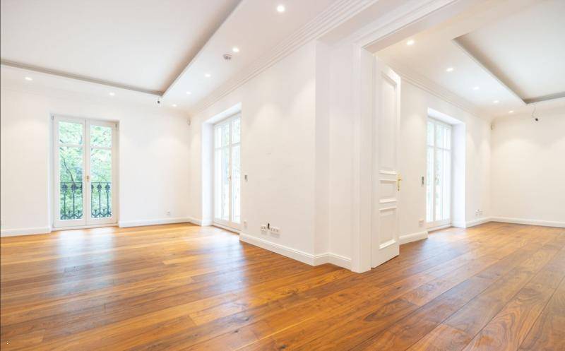 Heller Wohnraum mit Holzboden und mehreren französischen Balkonen, die viel Licht spenden.