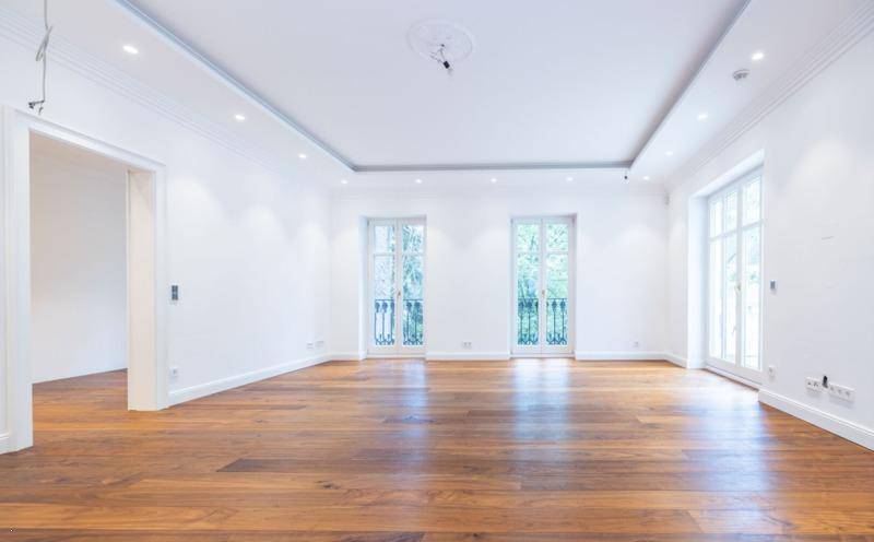 Geräumiges Zimmer mit Holzboden und drei französischen Balkonen, die den Raum erhellen.