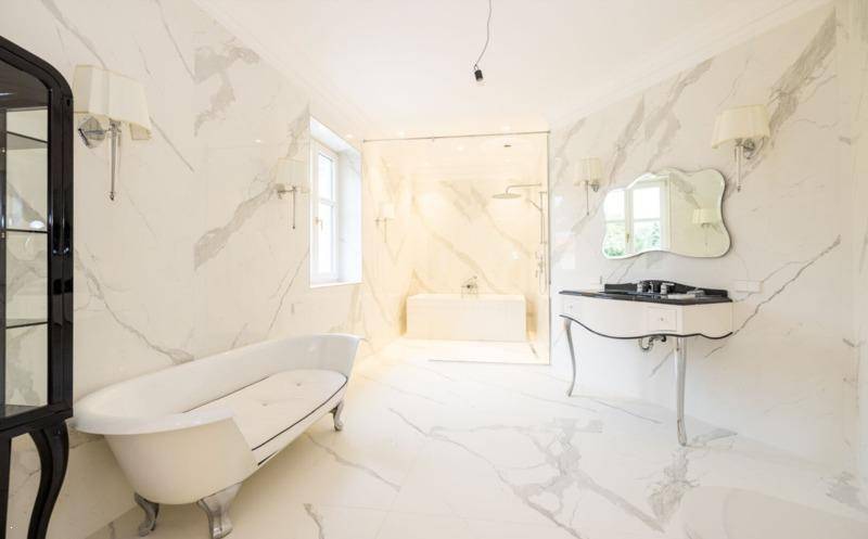 Großzügiges Luxusbadezimmer mit freistehender Badewanne, elegantem Waschtisch und Marmorwänden.