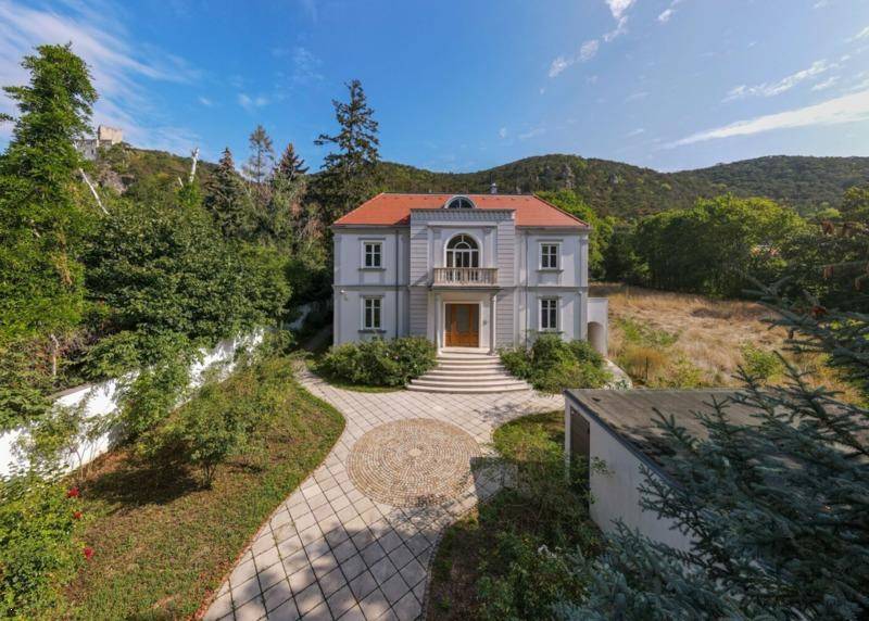 Repräsentative Villa mit klassischer Architektur, umgeben von viel Grün und einem geschwungenen Zufahrtsweg.