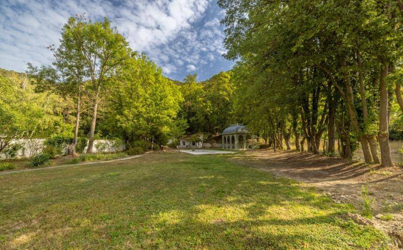 Weitläufiger Gartenbereich mit altem Baumbestand und einem charmanten Pavillon im Hintergrund.