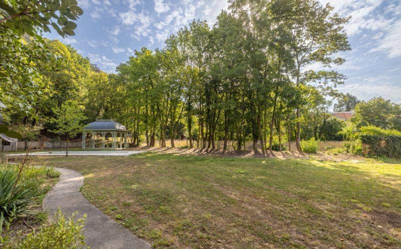 Idyllischer Garten mit üppigem Grün, altem Baumbestand und einem gewundenen Pfad.