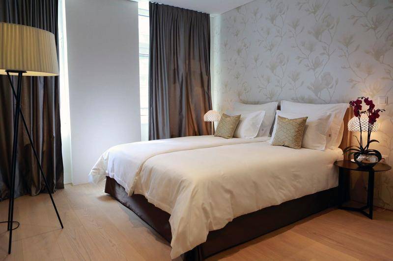 Helles Schlafzimmer mit zwei Einzelbetten, floraler Tapete und eleganten Vorhängen.